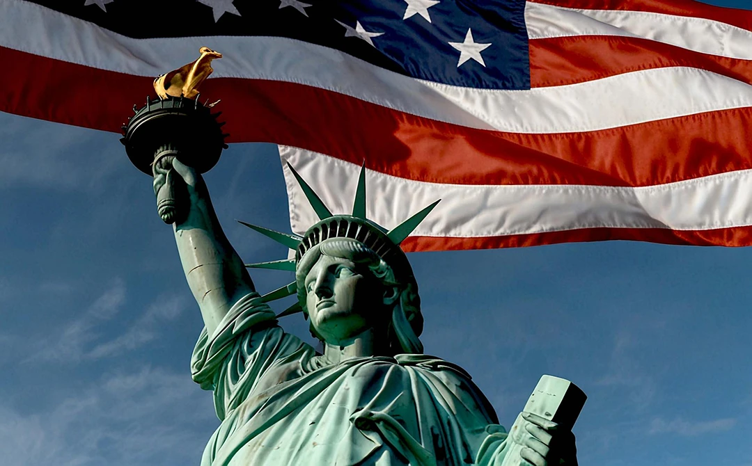 Statue of liberty with American flag waving in the background
